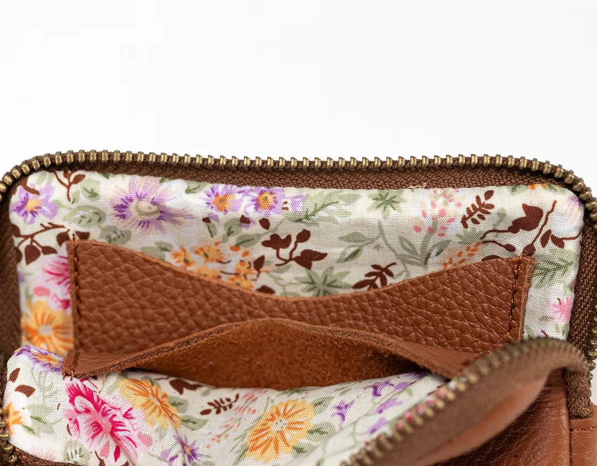 Close-up of a brown leather pouch with floral lining on a white background#color_brown