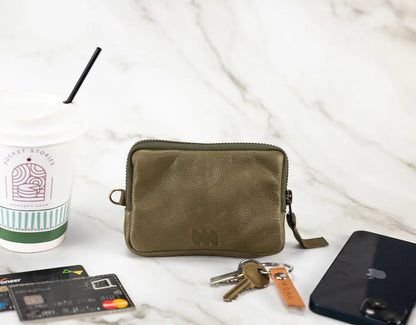 Green pouch with keys, phone, and cards on a white surface