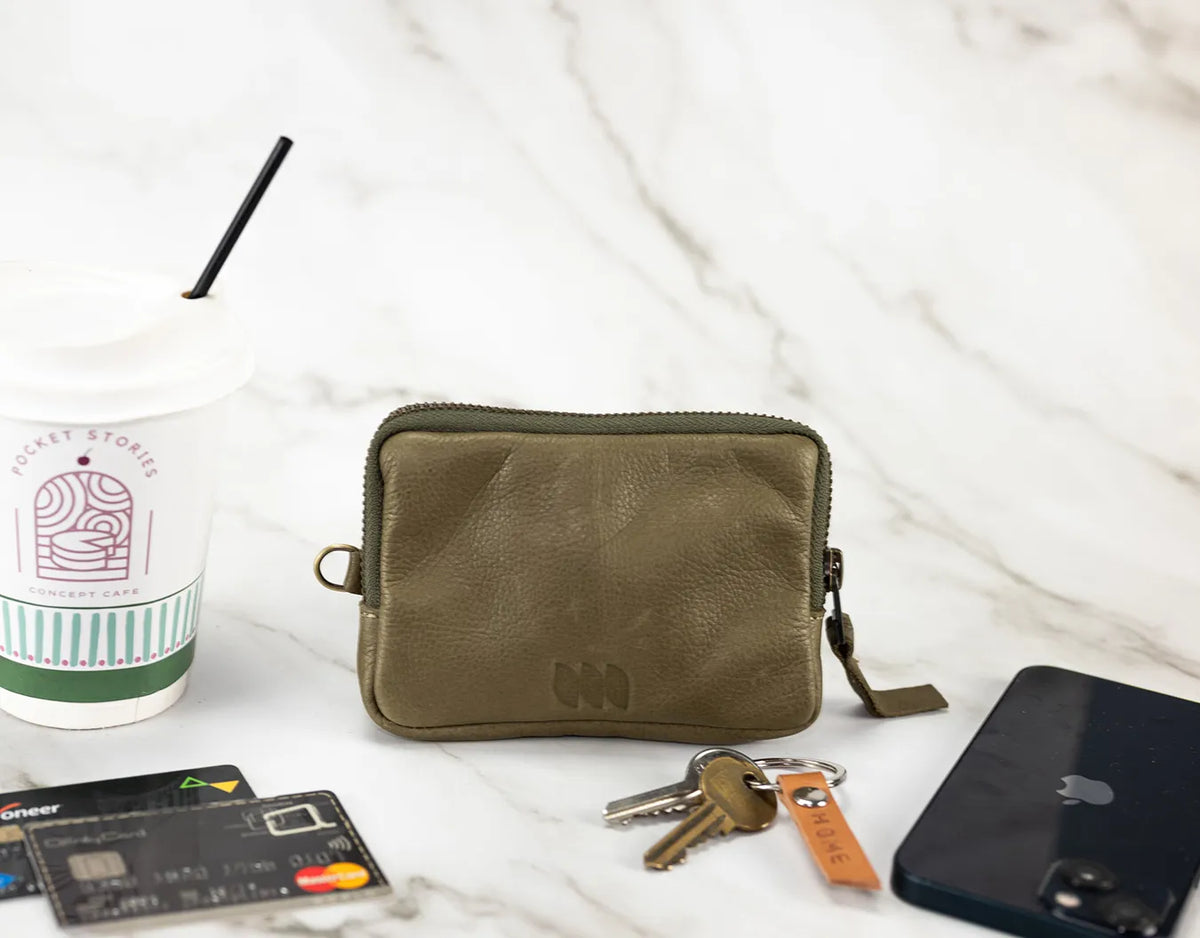 Green pouch with keys, phone, and cards on a white surface#color_olive-green