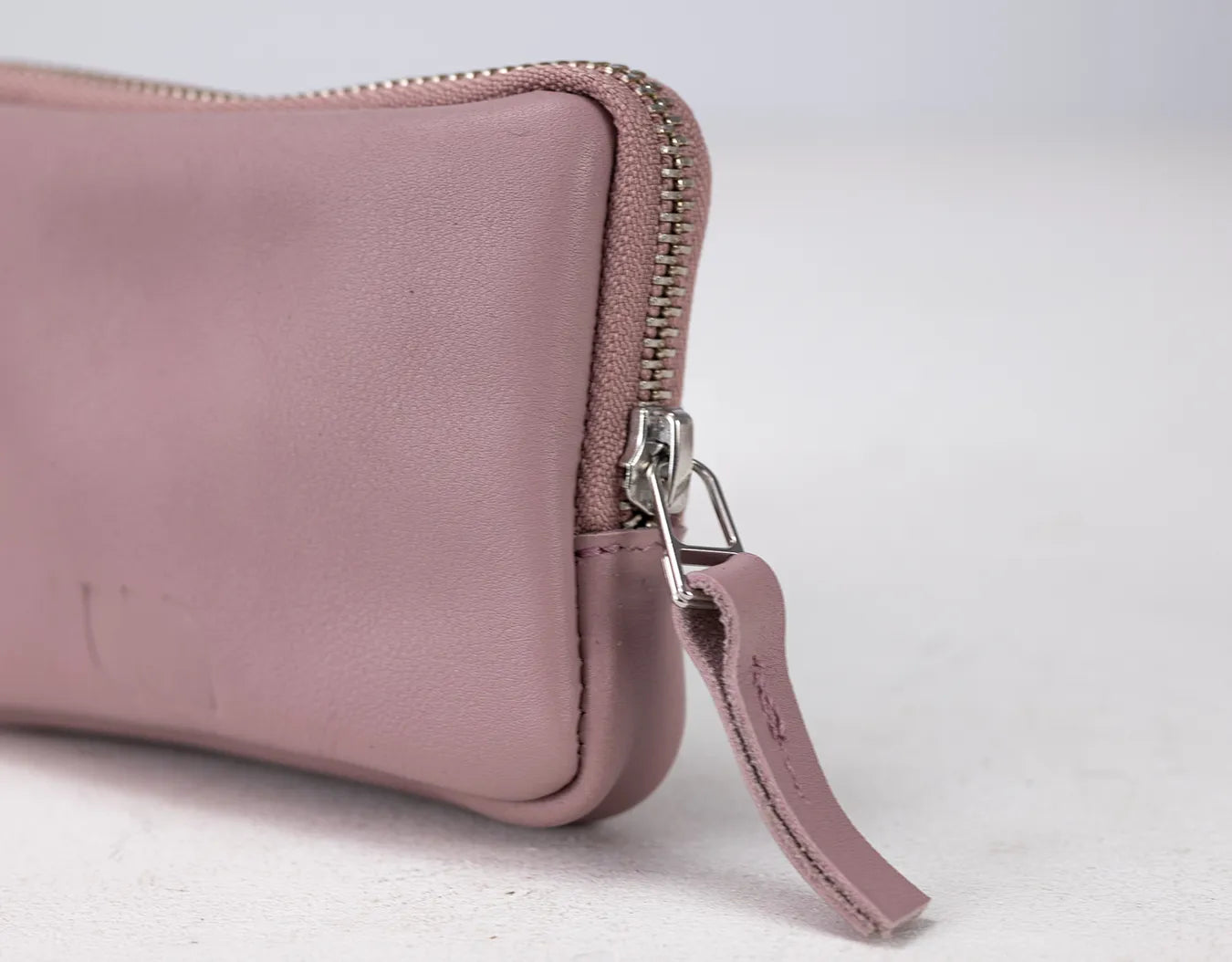 Pink leather wallet with a zipper on a light gray background