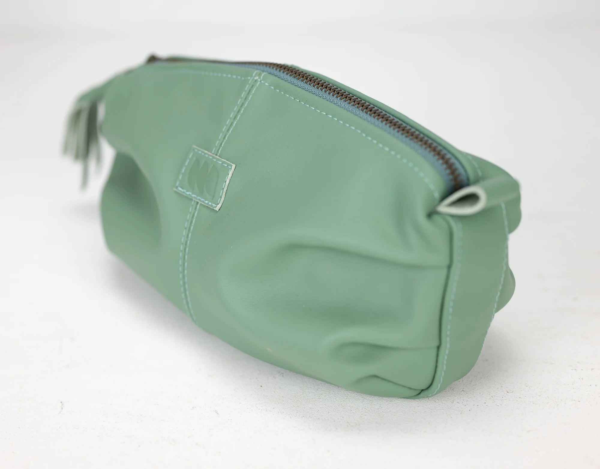 Green toiletry bag with a zipper on a white background