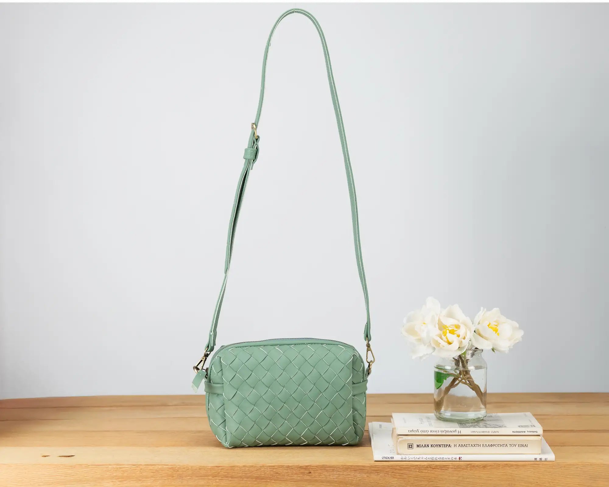 Green quilted handbag on a wooden surface with a white background