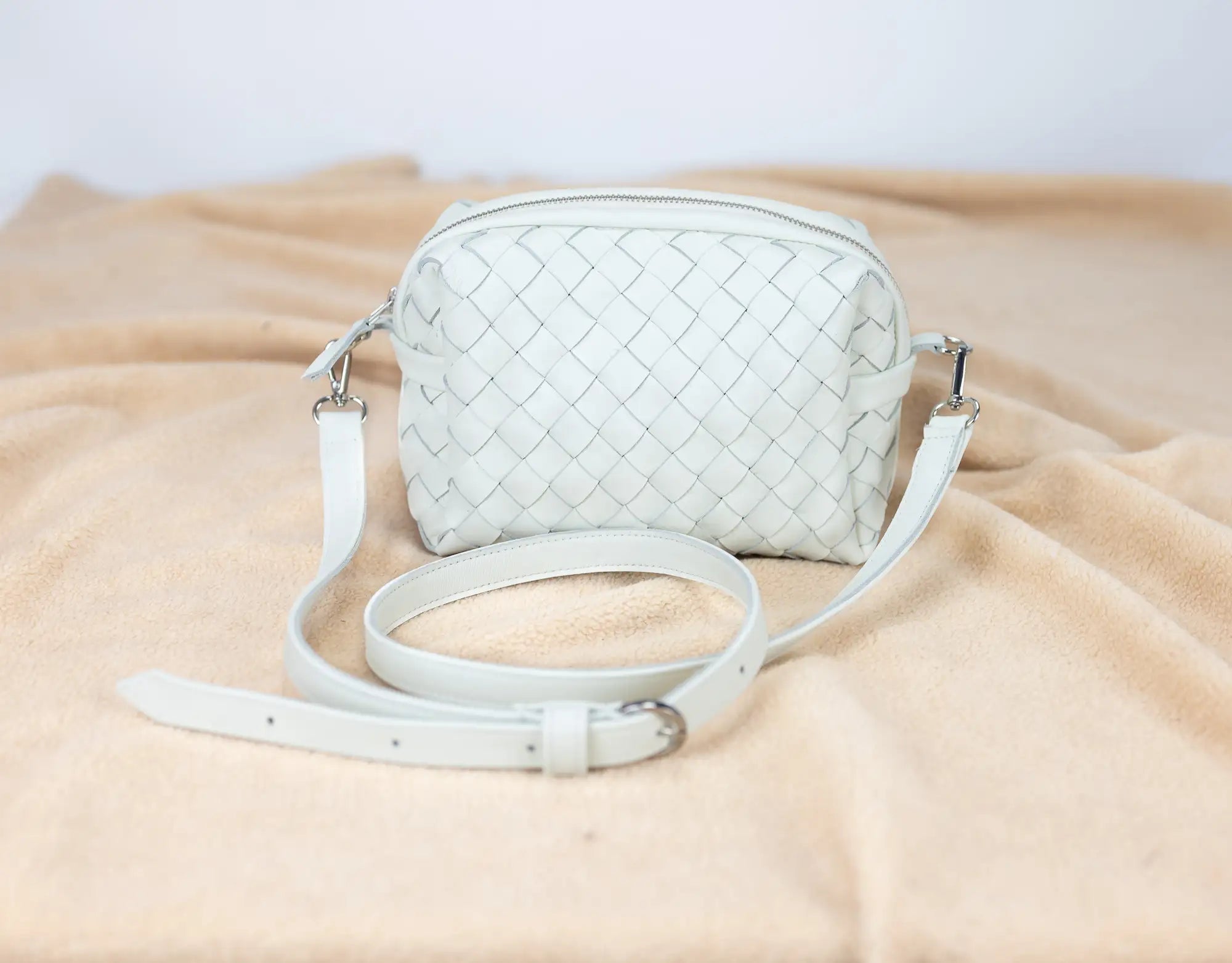 White woven handbag on a beige fabric background