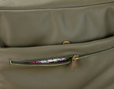 Close-up of a green leather bag with a floral patterned interior visible through a zipper.