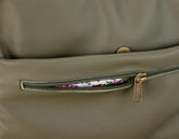 Close-up of a green leather bag with a zipper pocket showing floral lining.