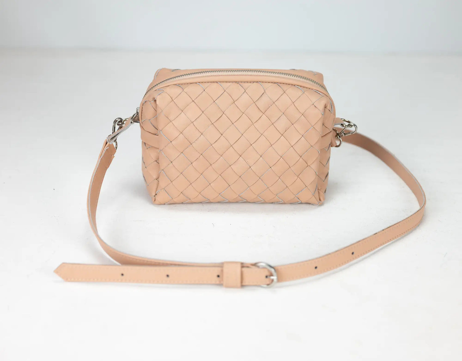 Beige woven handbag with a strap on a light gray background