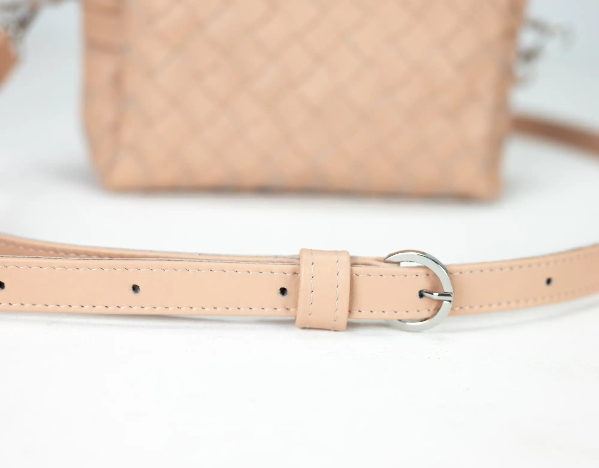 Beige leather belt with a buckle on a white background