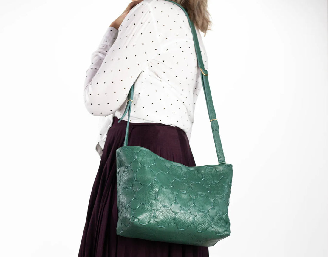 Green handbag worn by a person on a white background