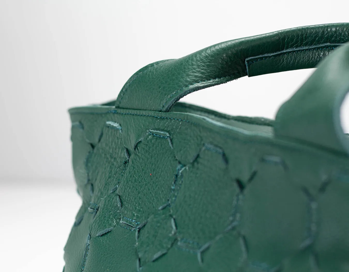 Green handbag with floral embossing on a white background
