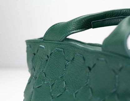 Green handbag with floral embossing on a white background