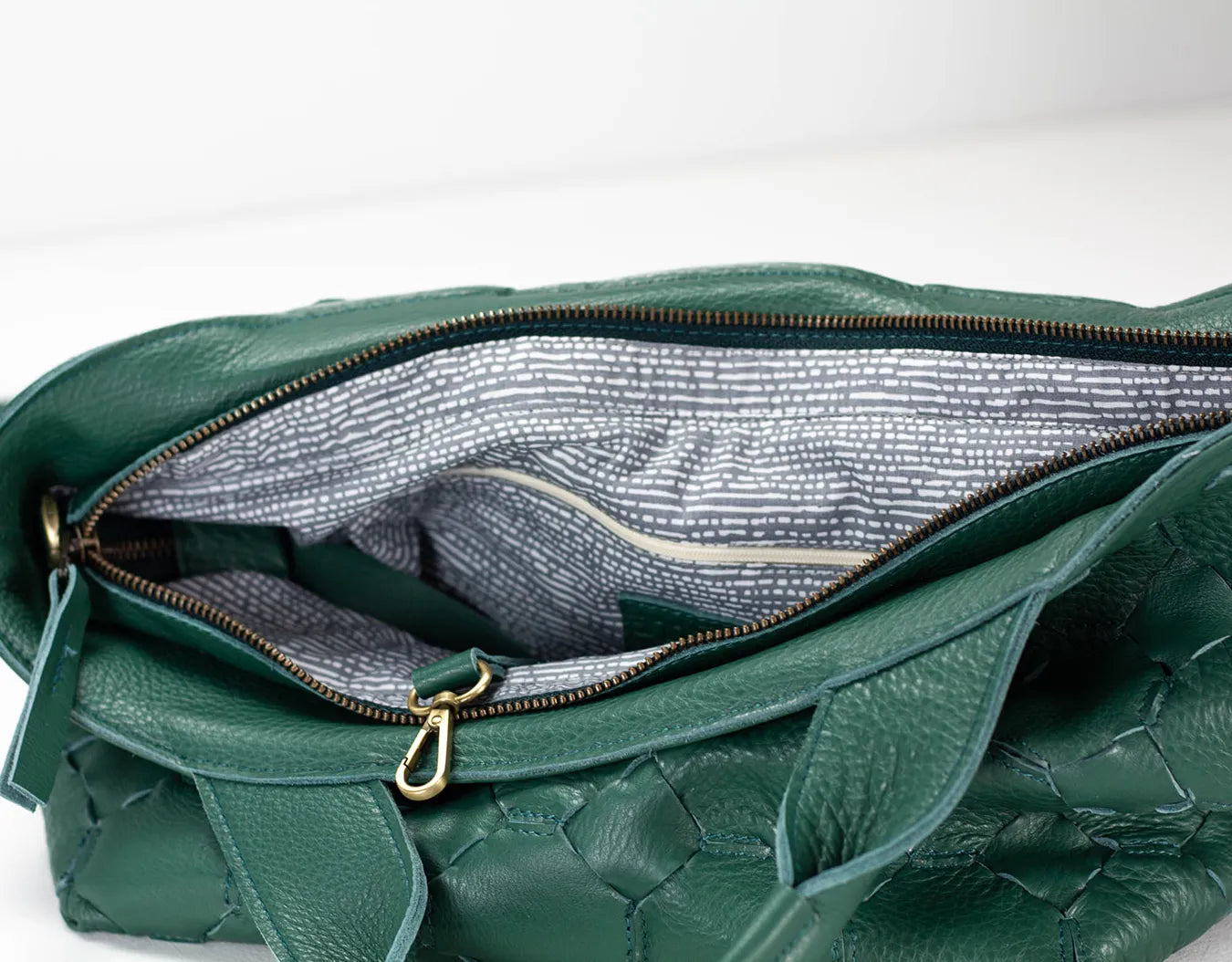 Green leather handbag with gold zipper on a white background