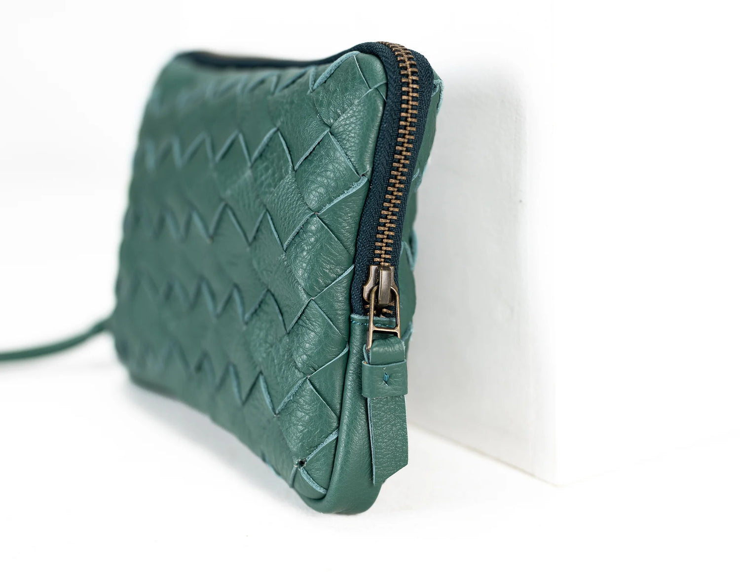 Green quilted clutch bag with a zipper on a white background