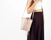 Woman holding a light pink handbag with a white background