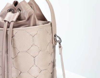 Beige textured handbag with drawstring and shoulder strap on a light gray background