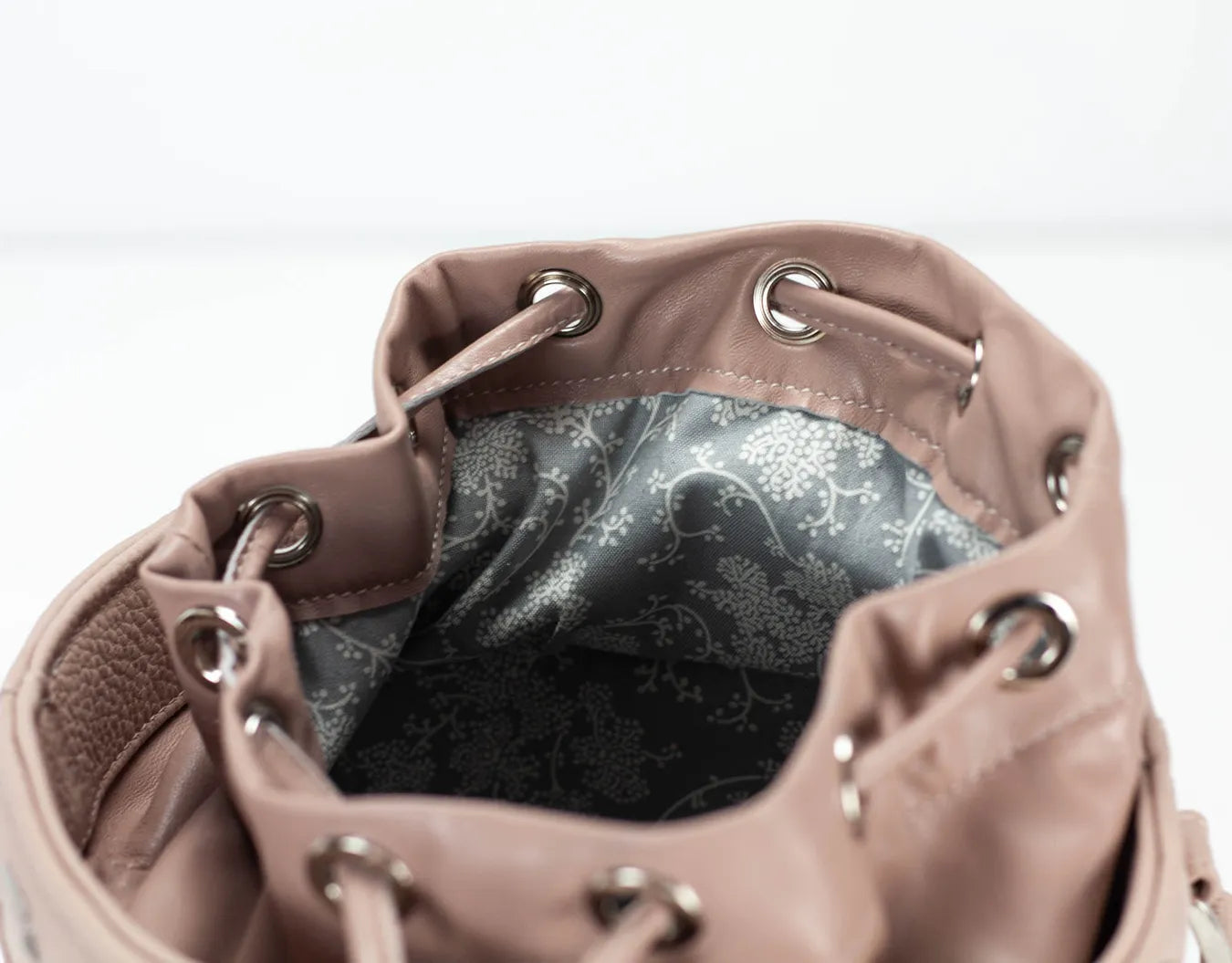 Close-up of a pink leather handbag with a floral patterned interior.
