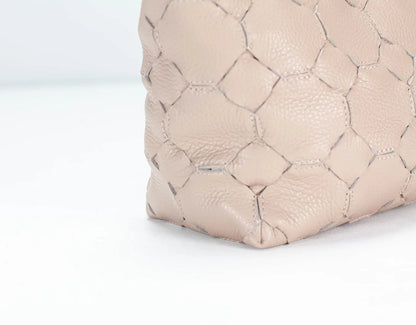 Close-up of a quilted beige handbag on a light gray background