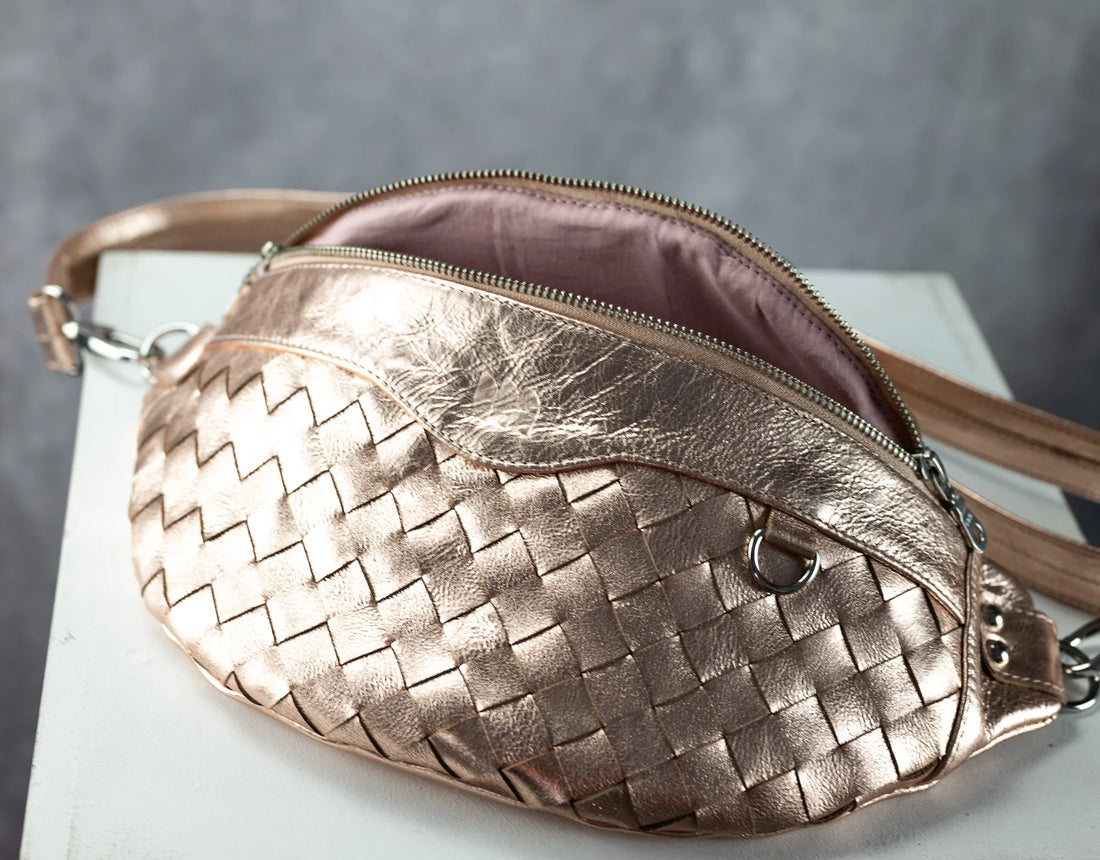 Rose gold woven handbag on a white surface with a gray background
