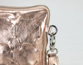 Rose gold metallic wallet with a chain detail on a light gray background