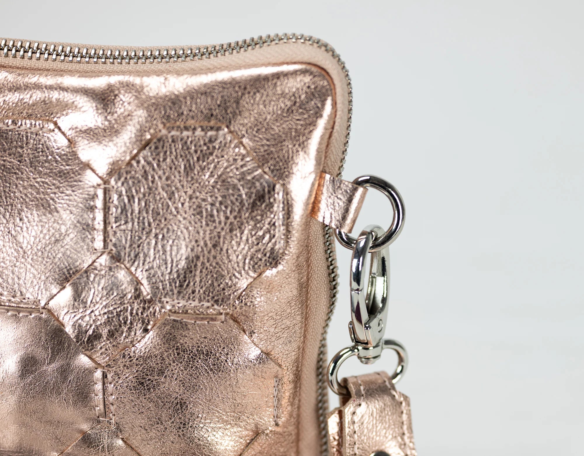 Rose gold metallic wallet with a chain detail on a light gray background