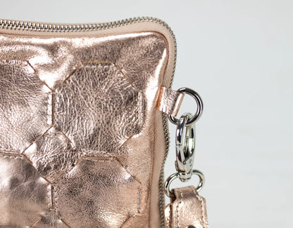 Rose gold metallic wallet with a chain detail on a light gray background