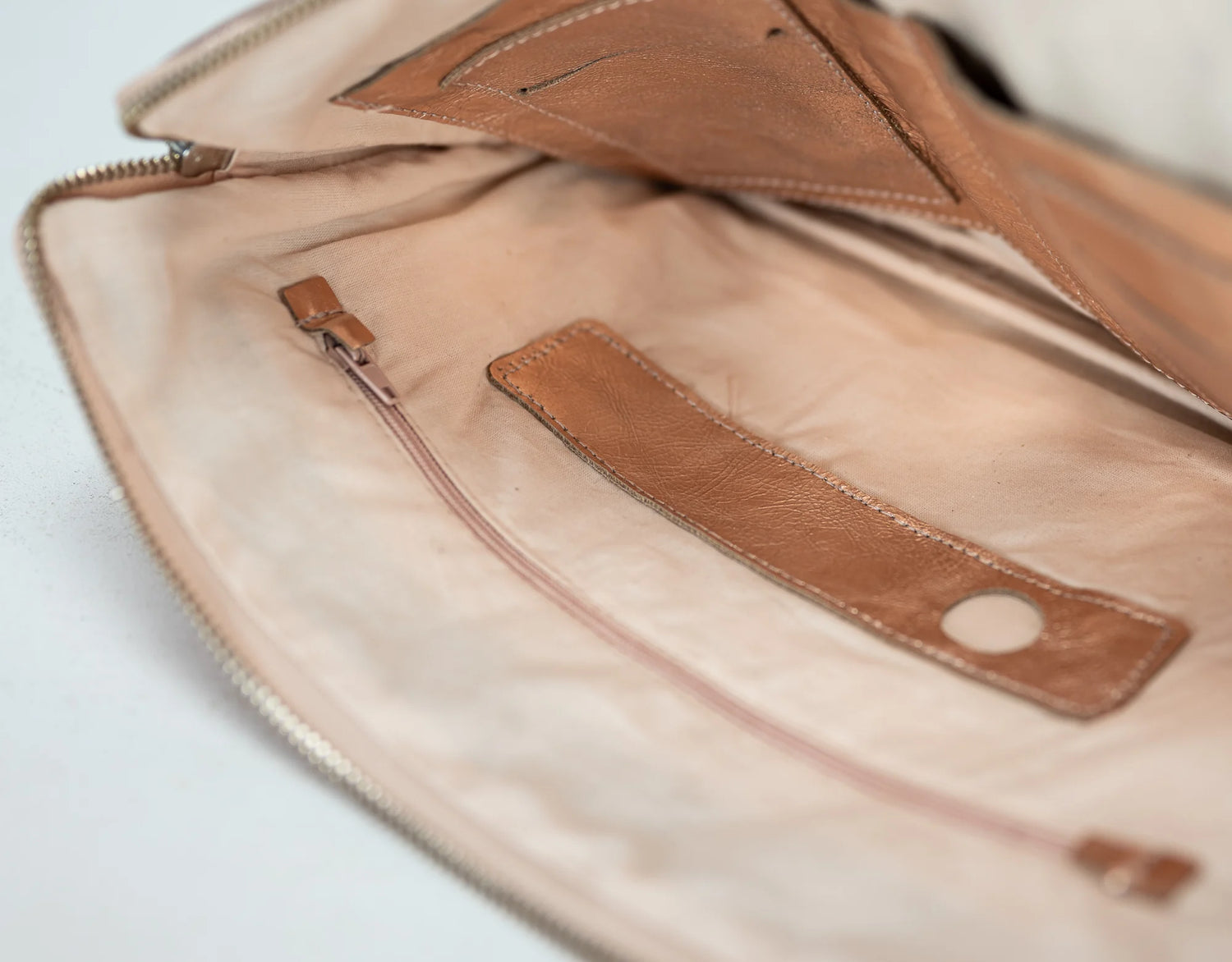 Close-up of a brown leather bag with a zipper on a light gray background