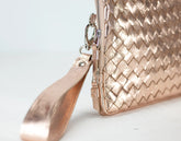 Rose gold clutch bag with textured pattern on a light gray background
