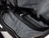 Close-up of the interior of a gray fabric bag with black textured trim and zipper details.