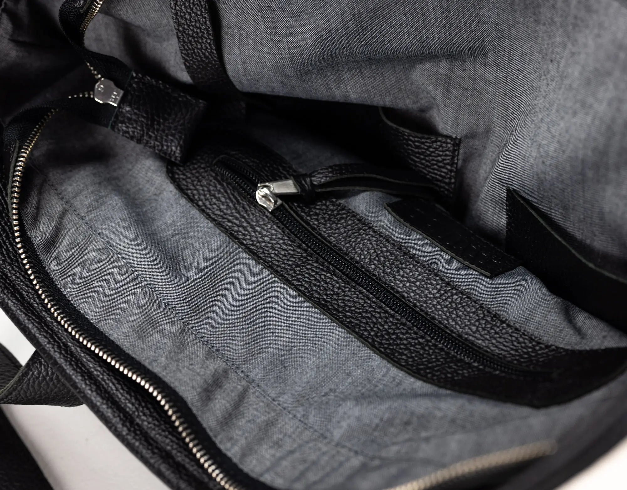 Close-up of the interior of a gray fabric bag with black textured trim and zipper details.