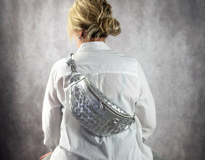 Person wearing a silver reflective fanny pack against a gray background