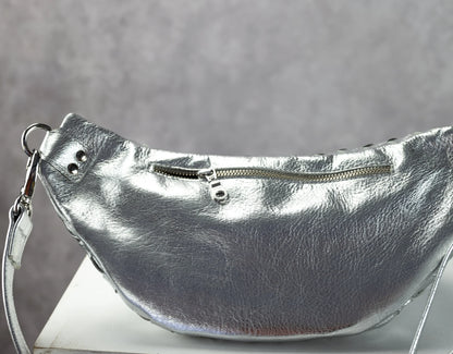 Silver leather handbag with a strap on a gray background