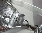 Close-up of a silver leather handbag with a strap on a white background