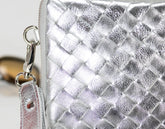 Silver woven handbag with a strap on a blurred background