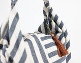 Blue and white striped bag with a brown tassel on a white background