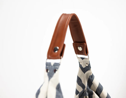 Striped bag with a brown leather strap on a white background