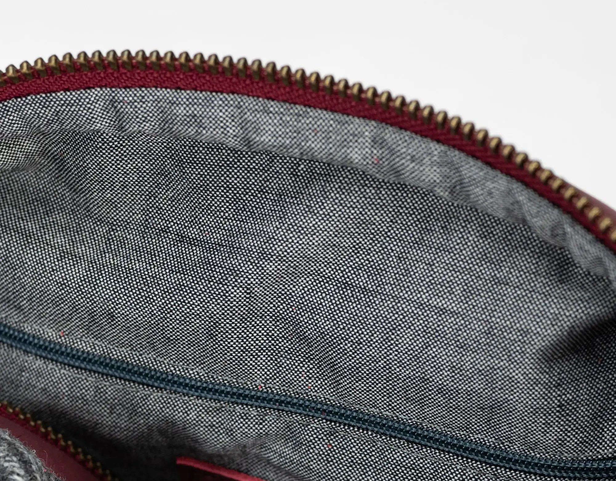 Close-up of a gray fabric interior with a red zipper on a white background