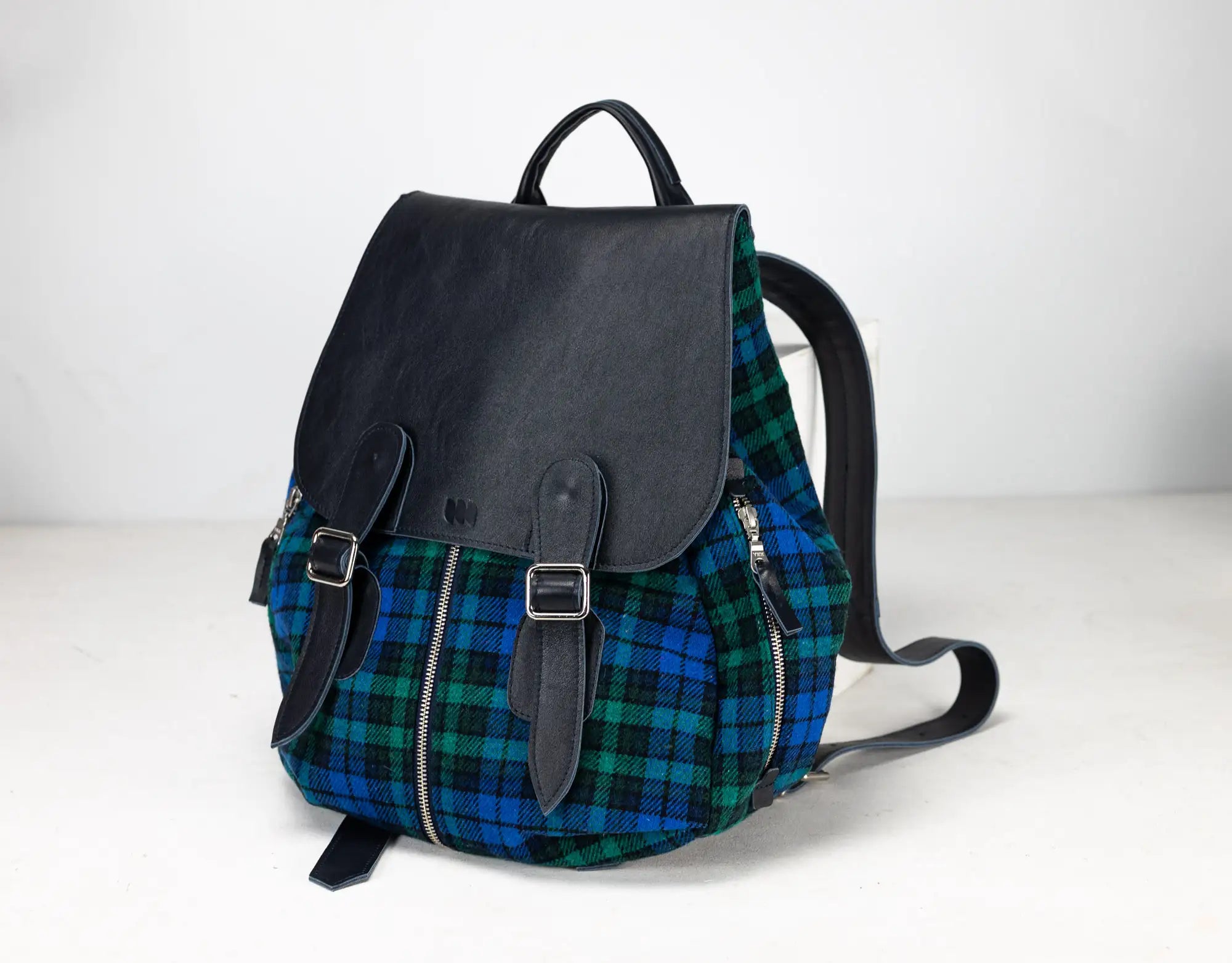 Black leather and plaid fabric backpack on a white background