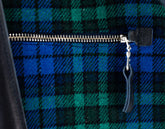 Close-up of a blue and green plaid fabric with a zipper and keychain.