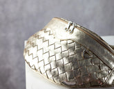 Gold woven handbag on a gray background