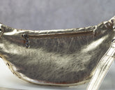 Metallic yellow gold fanny pack with a zipper on a gray background