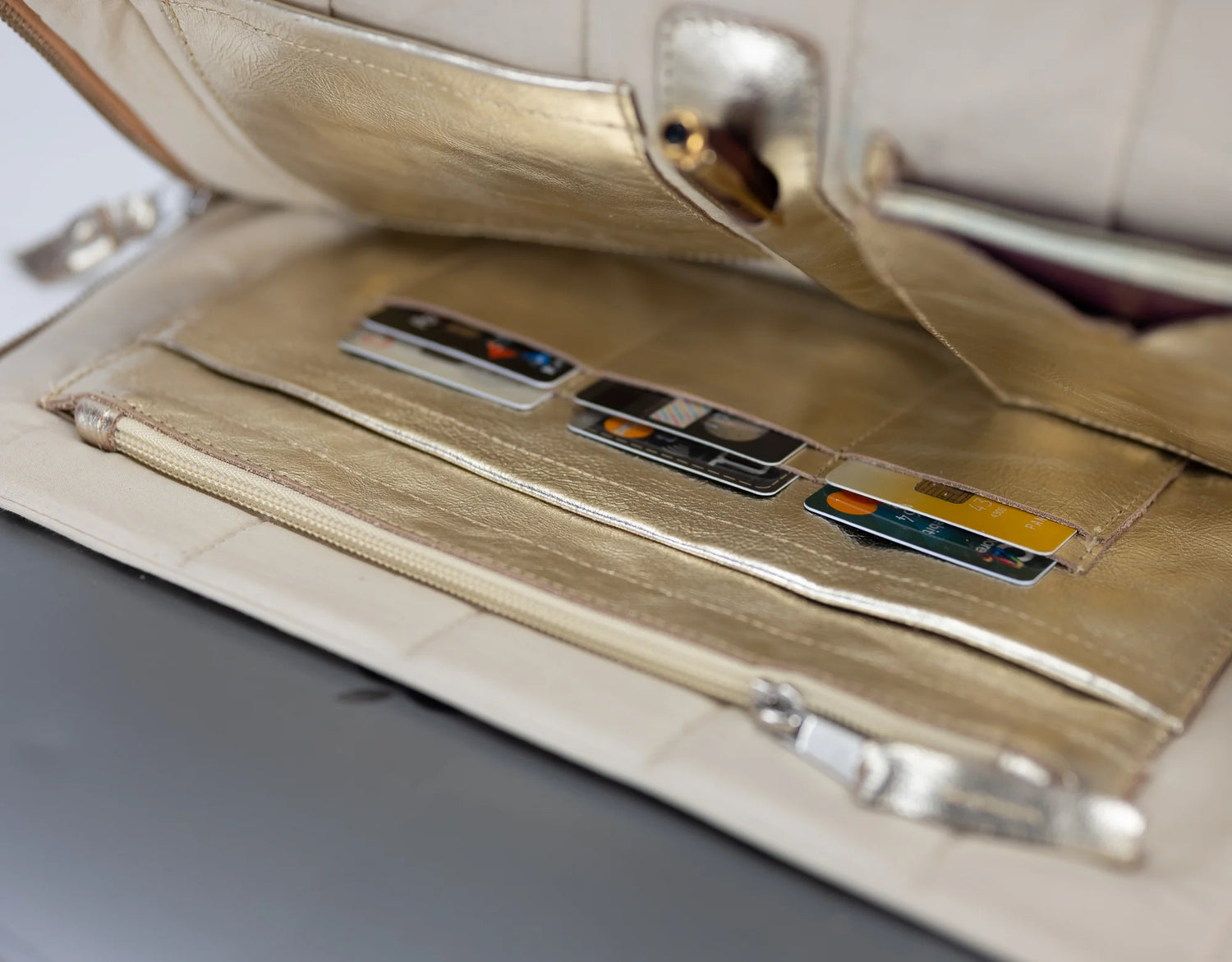 Beige wallet with card slots and a zipper pocket on a gray surface