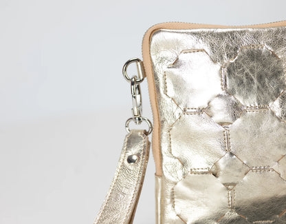 Metallic gold handbag with a strap on a light gray background