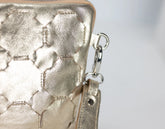 Close-up of a gold textured handbag with a keychain on a light gray background
