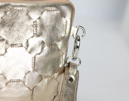 Close-up of a gold textured handbag with a keychain on a light gray background