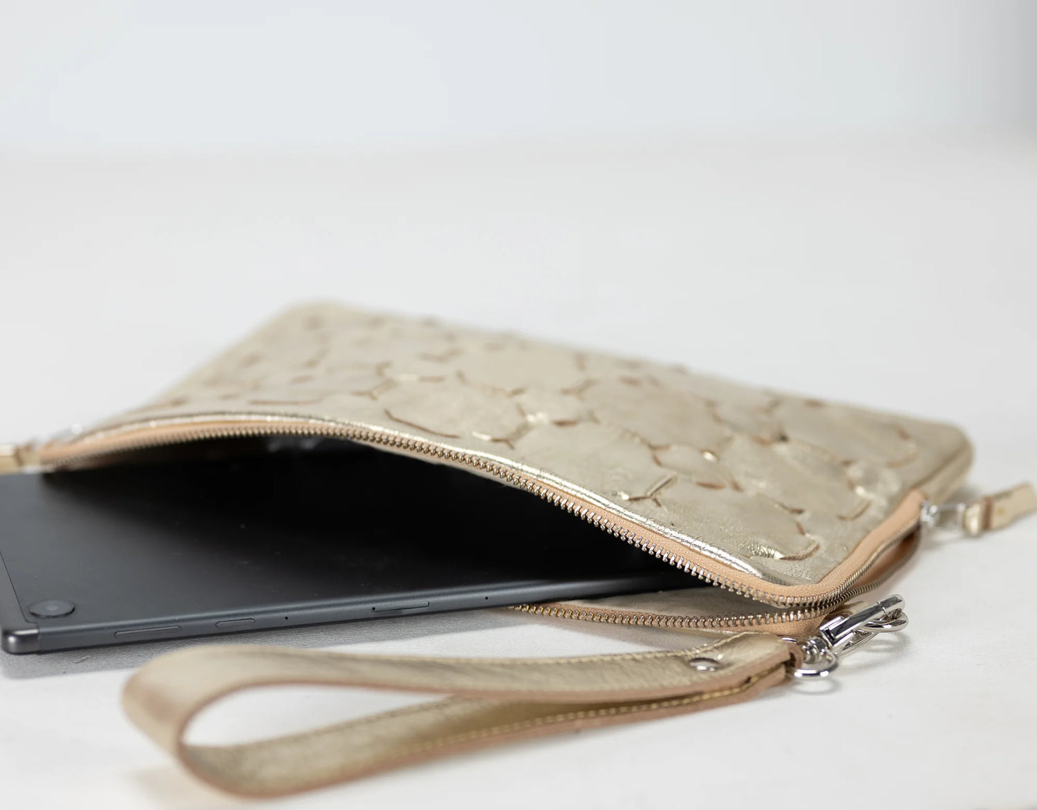 Yellow gold quilted clutch bag with a phone and cards on a white background