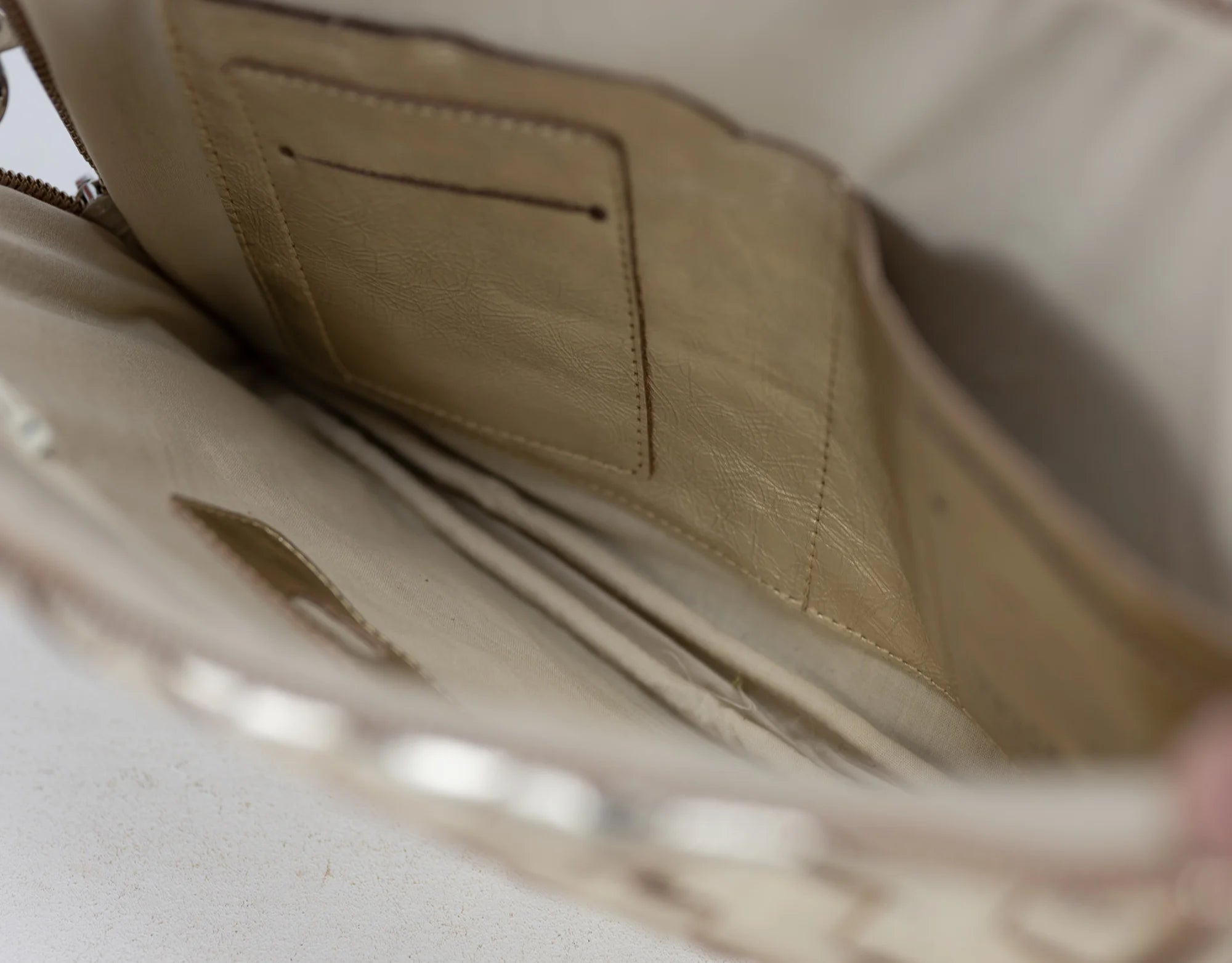 Close-up of a beige leather bag with a zipper on a light background