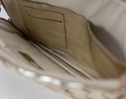 Close-up of a beige leather bag with a zipper on a light background 