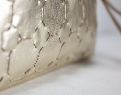Close-up of a quilted beige handbag on a light background