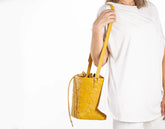 Person holding a yellow textured handbag against a white background