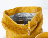Yellow textured handbag with a white interior on a light gray background