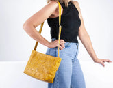 Person holding a yellow handbag with a plain background